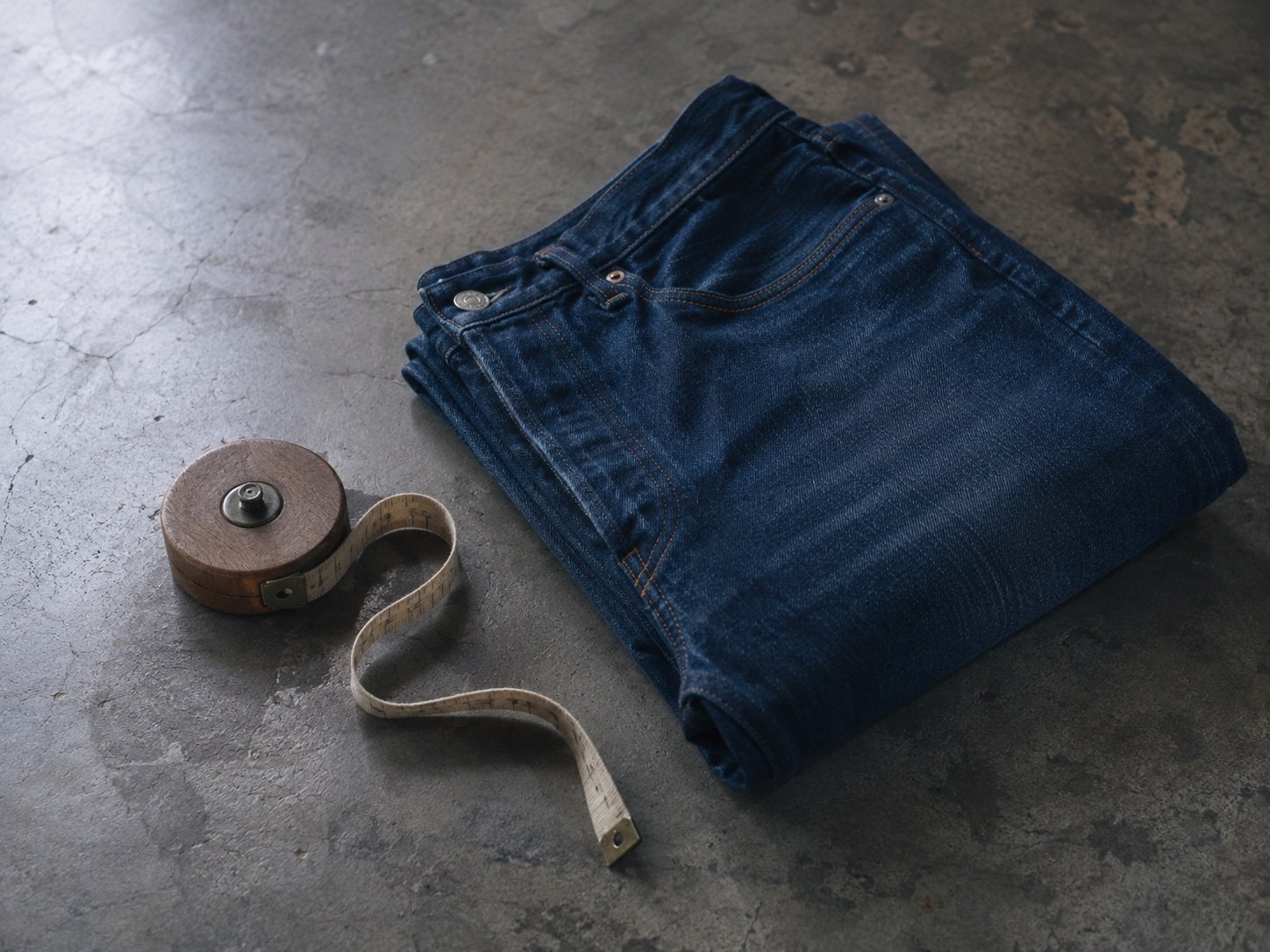 A folded ribbed knitted sock beside an uncoiled cloth tape measure